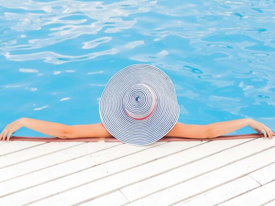 Image of a lady in a hat relaxing in a swiming pool for 's Top VIP Beach Clubs Quinta do Lago - GlamPortugal
